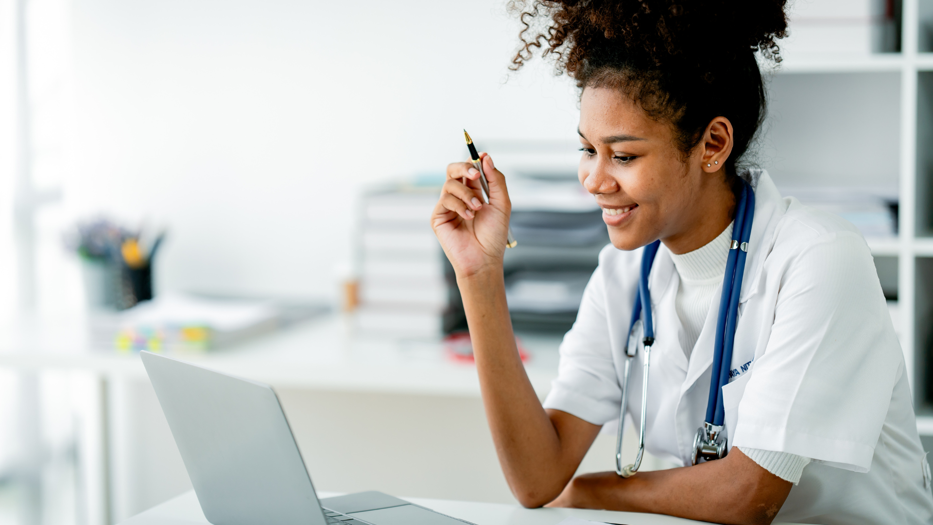 a female doctor working on a laptop with a pen in her hand