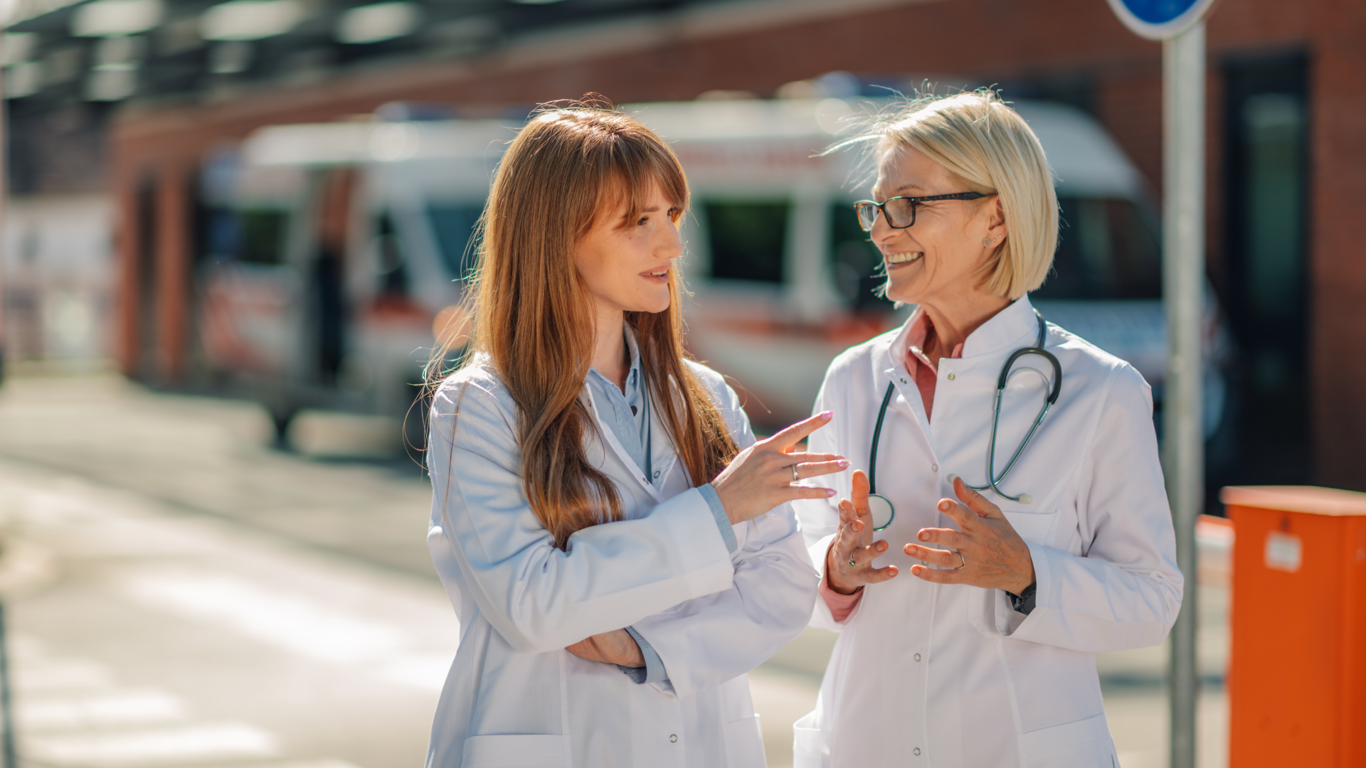 Two women doctors talking outside a hospital