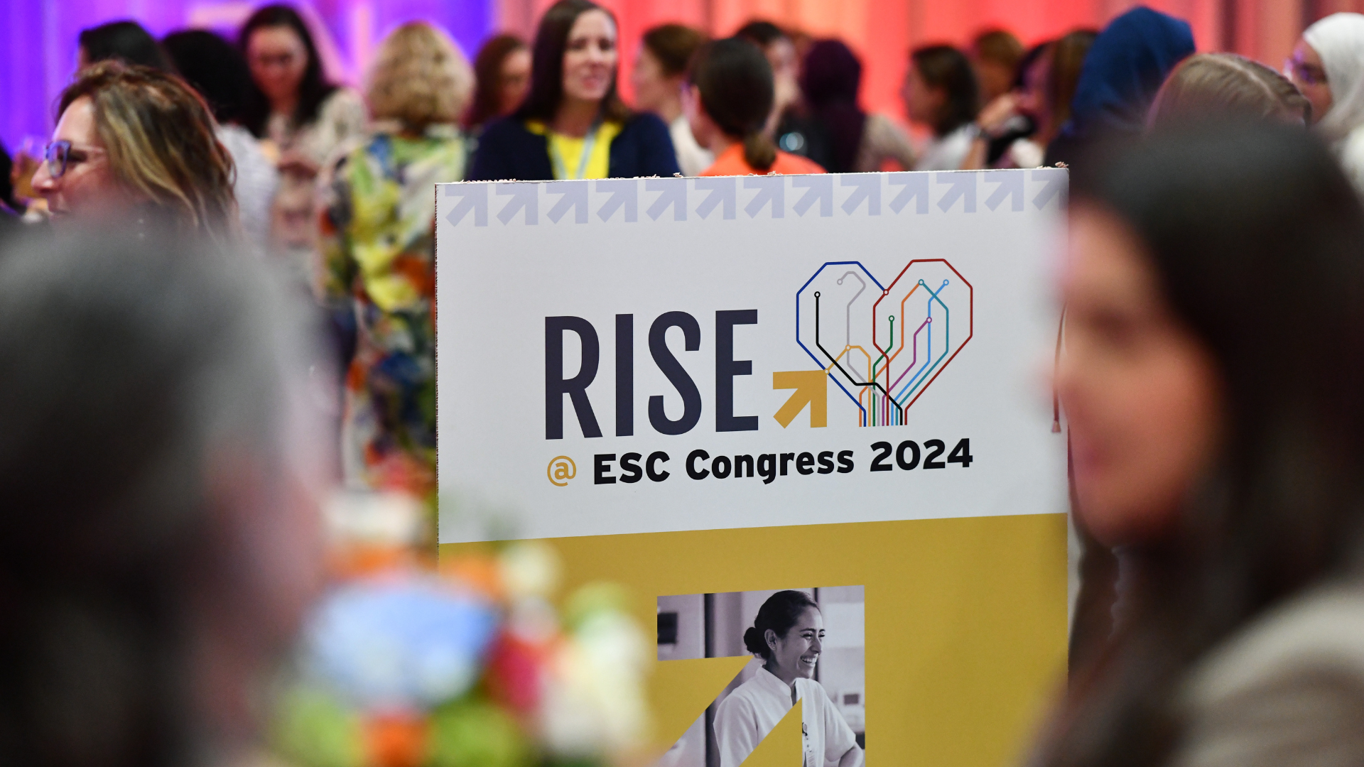 RISE @ ESC Congress 2024 promotional board in the middle of a crowded room