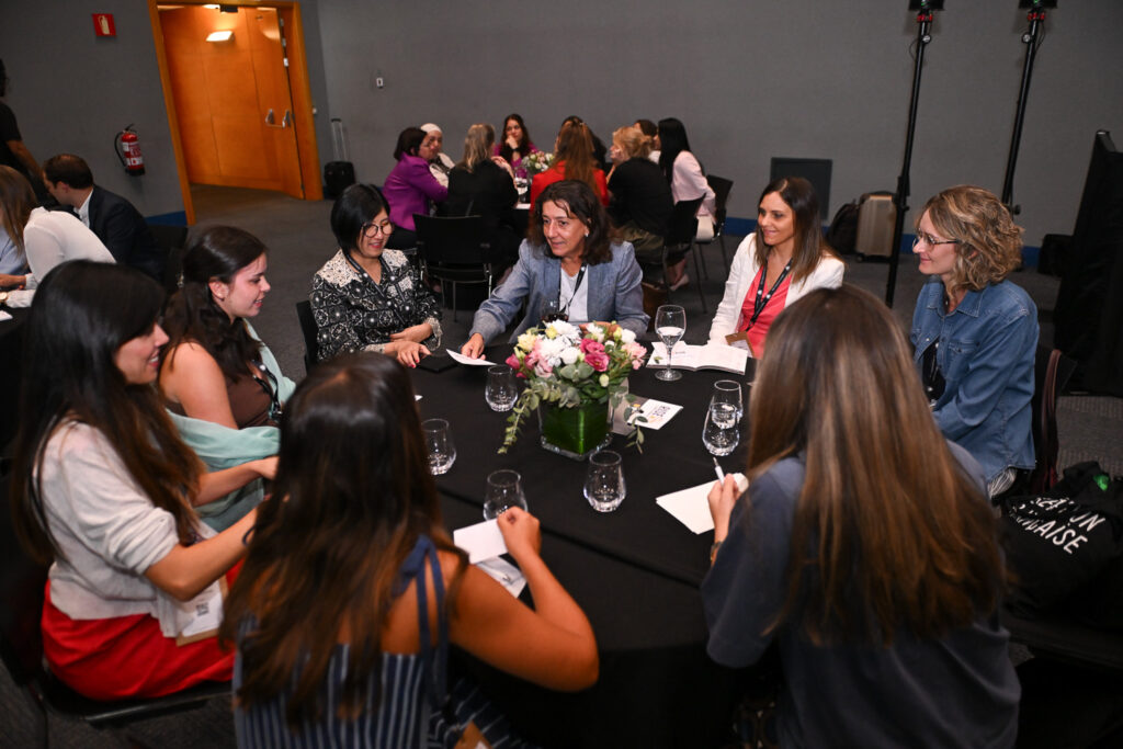 Group of women cardiologists sat around a table having a conversation during a conference