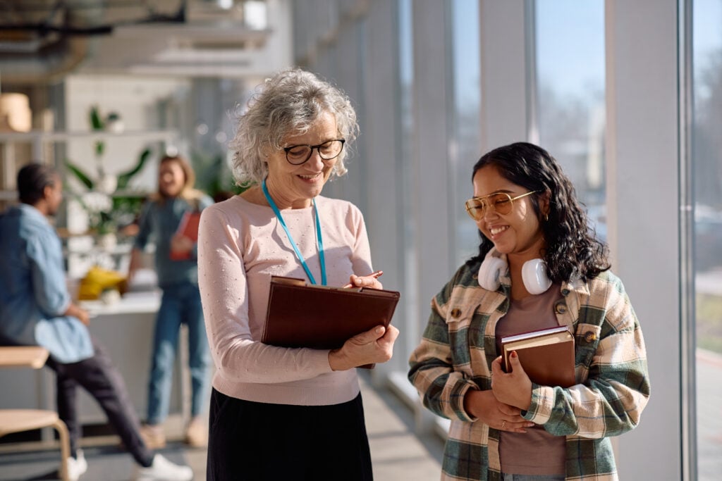 Older professional woman talking and smiling with a woman student