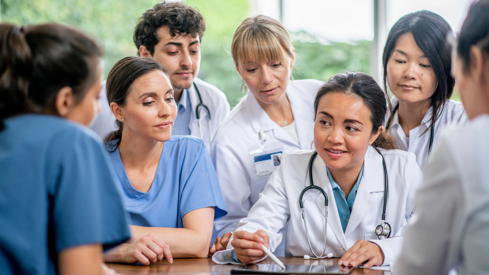 A group of predominantly women physicians reviewing paperwork about women's leadership around a table
