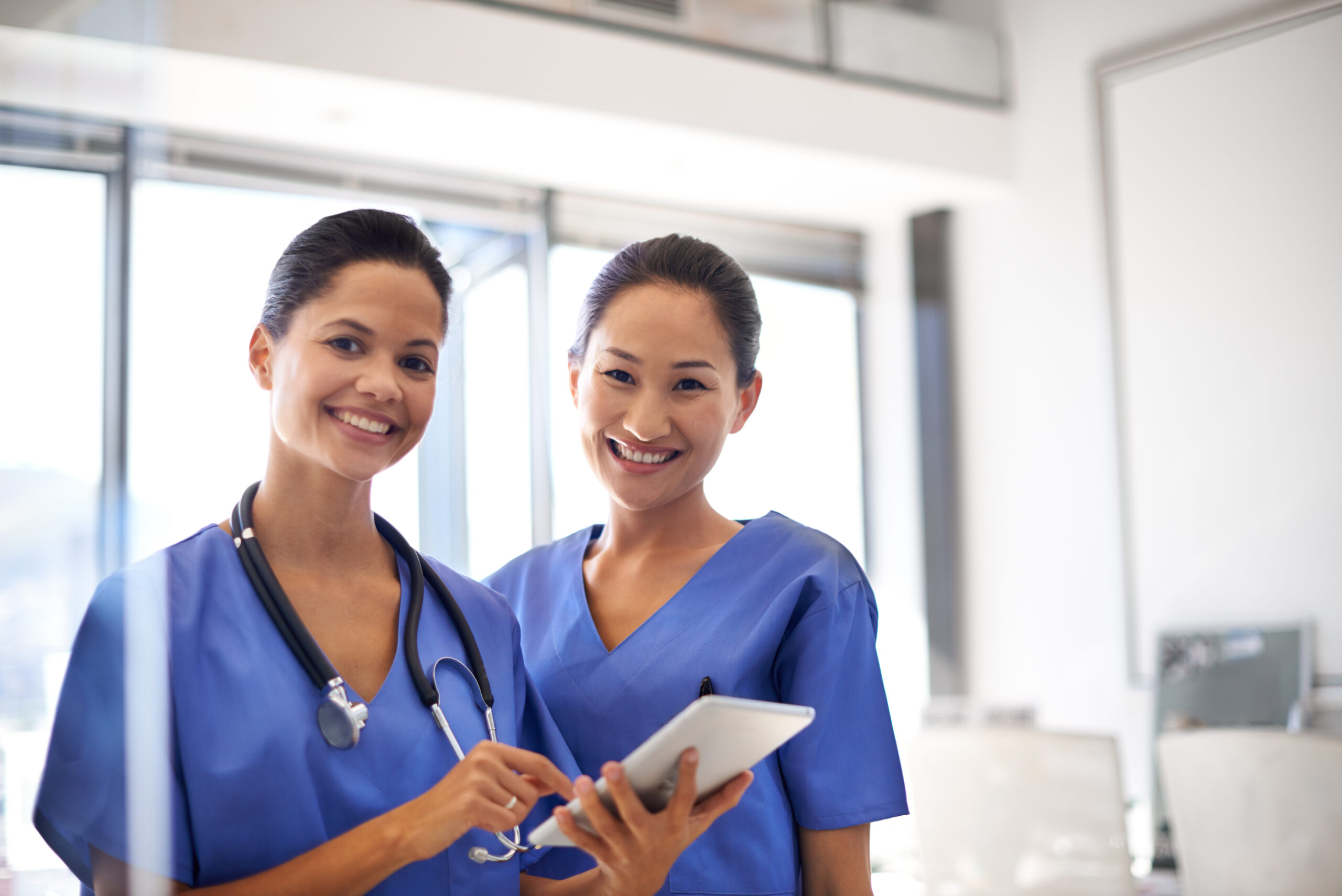 Portrait of two women physicians standing with a digital tablet in a hospital.