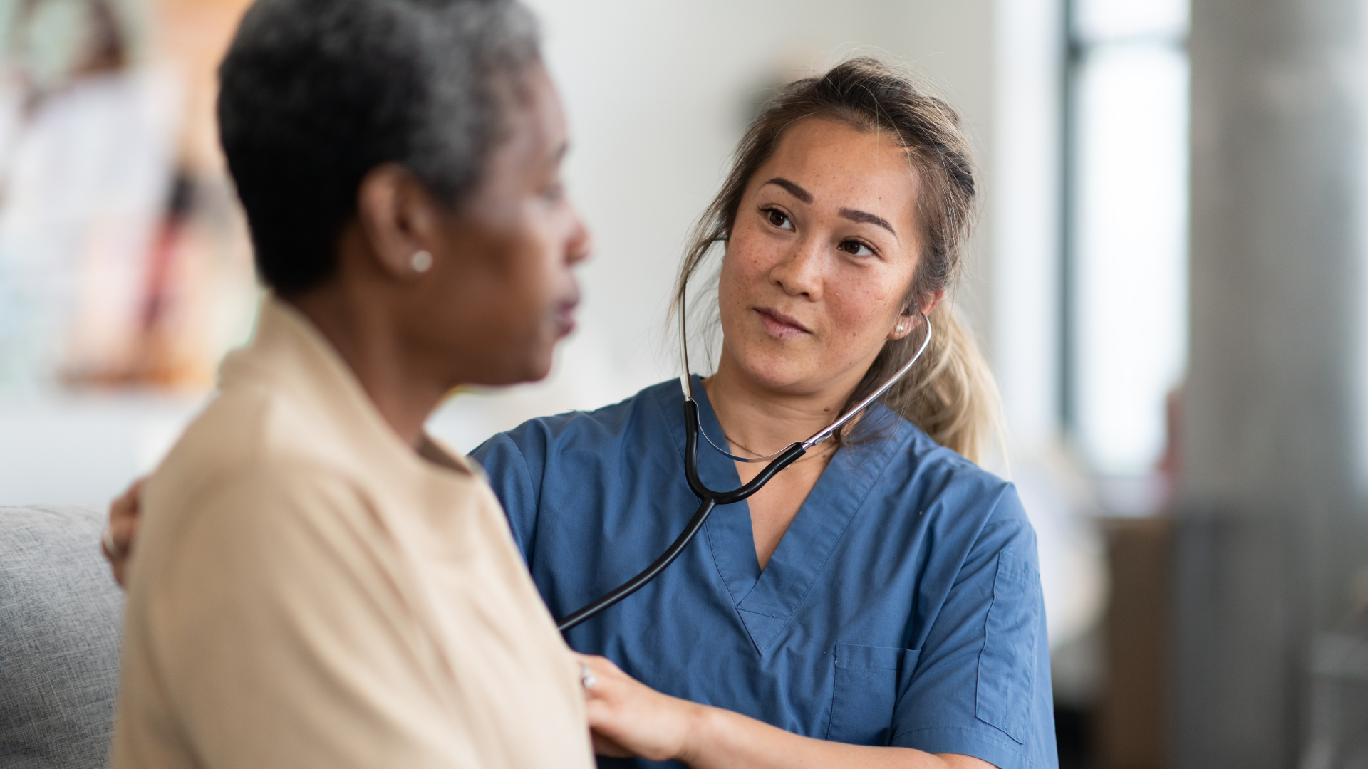 A woman physician holding a stethoscope to the chest of a woman patient checking for cardiovascular disease