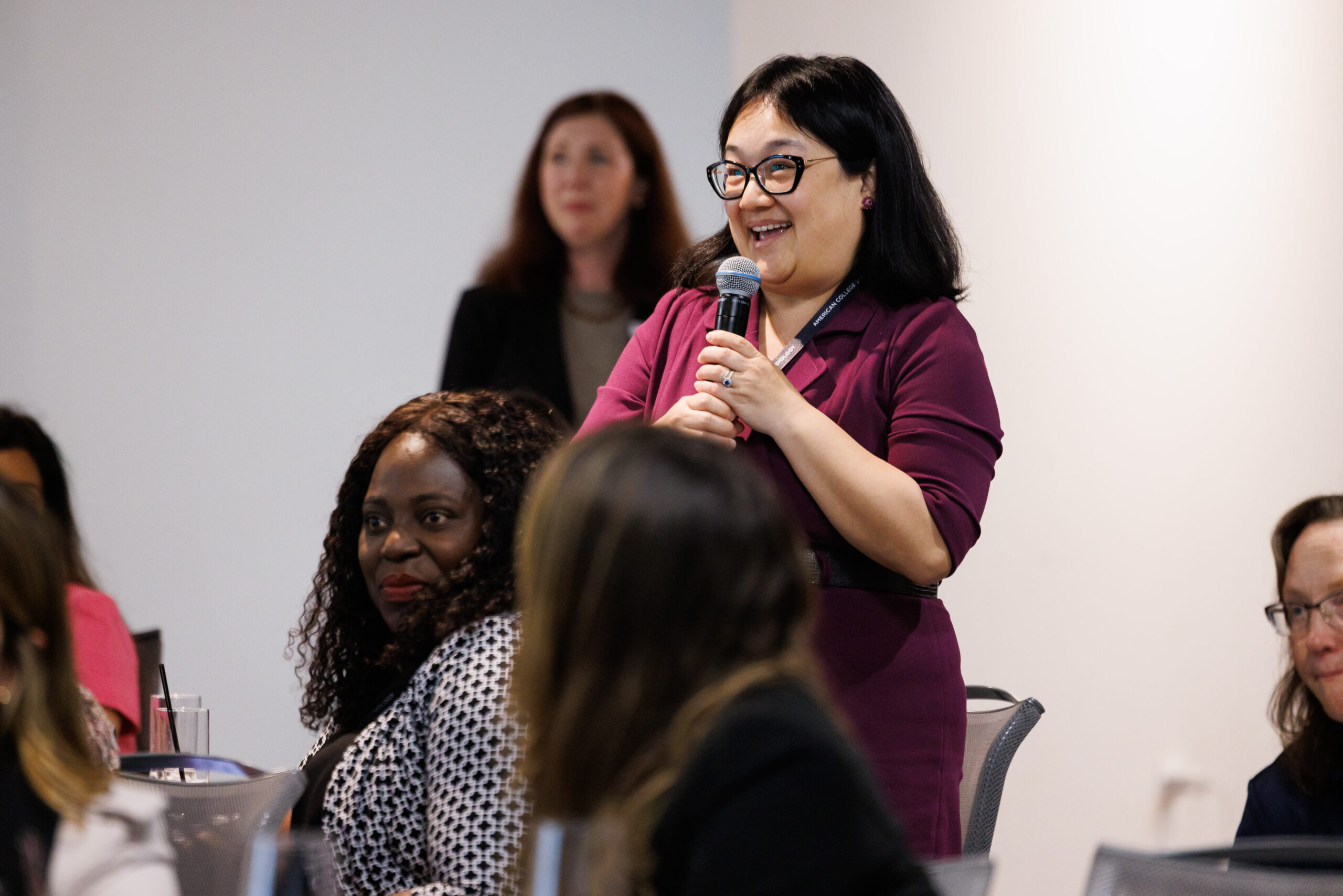 For Partners 6 Woman stood during an event speaking into a microphone